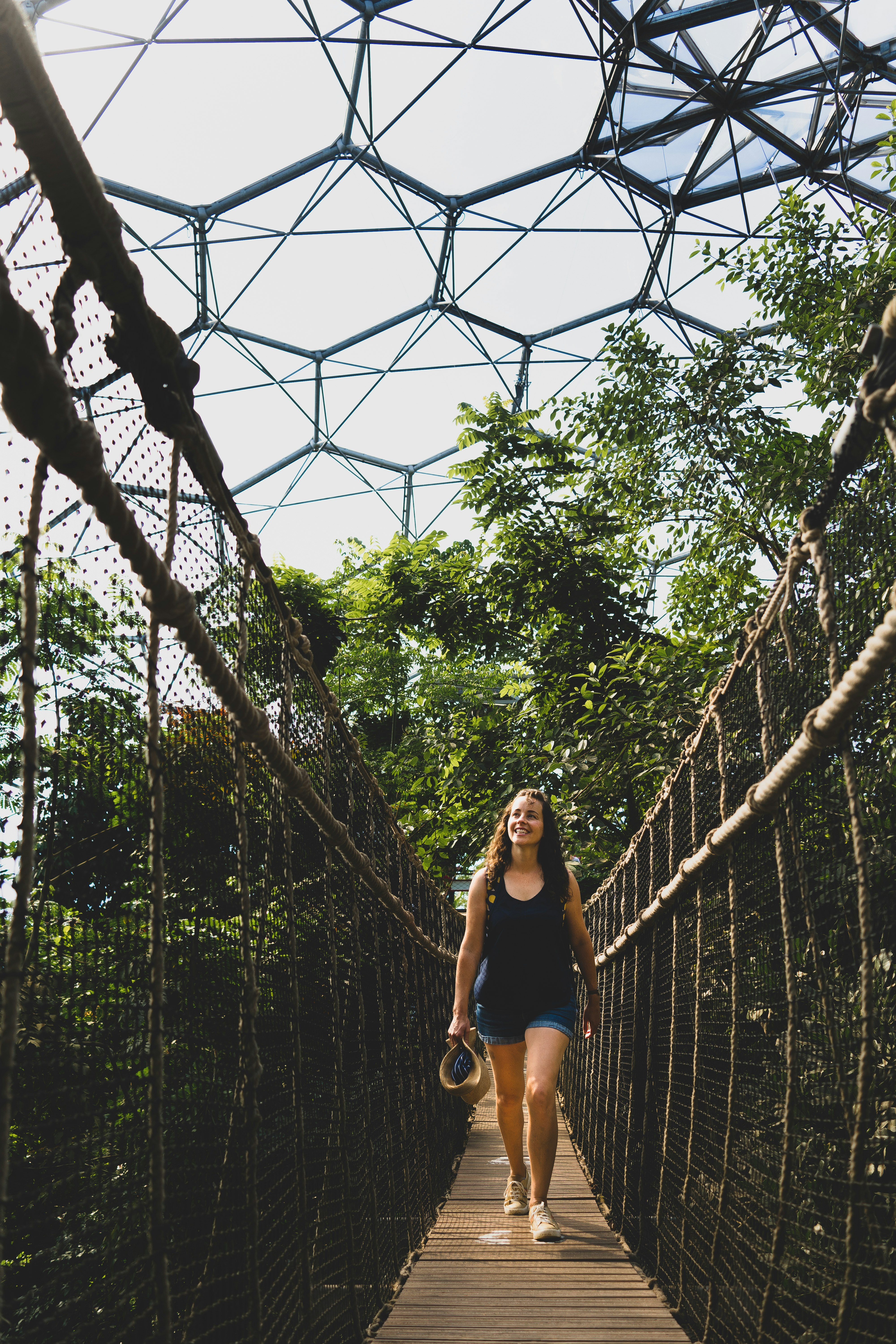 woman in black tank top and black shorts standing on hanging bridge during daytime